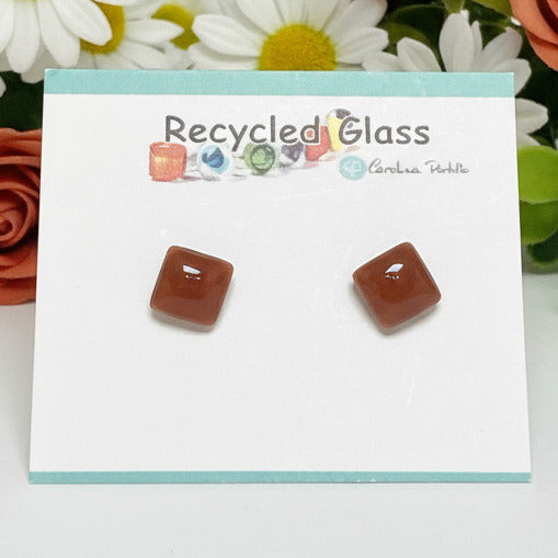 Pair of handcrafted square stud earrings made from translucent warm brown recycled glass, displayed on a clean background to showcase the unique texture and geometric shape.
